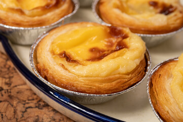 Portugal's traditional sweet dessert Pastel de nata egg custard tart pastry in cup close up on wooden background