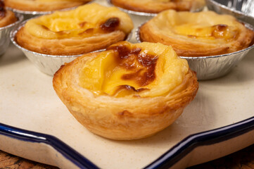 Portugal's traditional sweet dessert Pastel de nata egg custard tart pastry in cup close up on wooden background
