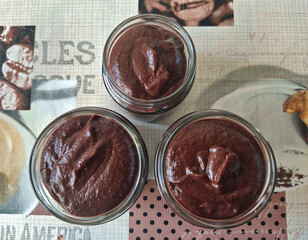 Homemade chocolate mousse in a glass jar on a tablecloth