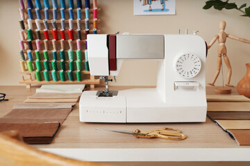 Sewing machine with fabric samples on tailor's table in atelier