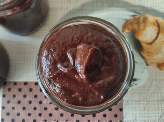 Homemade chocolate mousse in a glass jar on a tablecloth