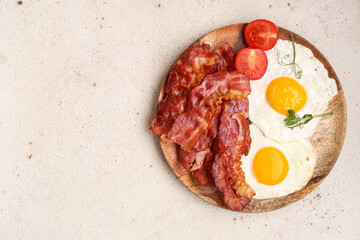 Plate with fried eggs, bacon and tomatoes on white background. Top view