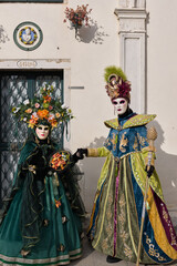 Fototapeta premium Venice, Italy - People dressed in carnival masks are photographed by tourists in the scenery of the ancient Venetian palaces