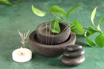 Obraz premium Acupuncture needles, candle and spa stones on green background