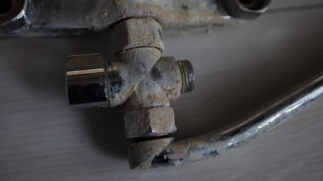 A rusty water faucet. Outdated plumbing. A broken faucet with lime coating.