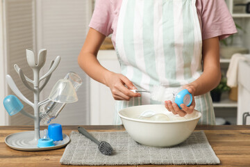 Woman with brush cleaning baby bottle at counter in kitchen, closeup