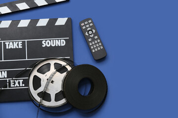 Movie clapper with remote control and film reels on blue background