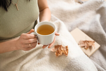 Woman in plaid holding cup of green tea in room. Closeup