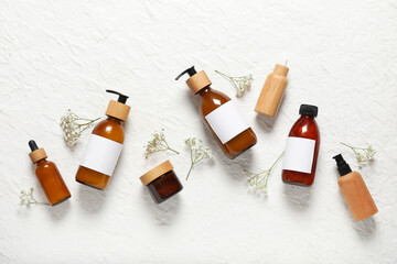 Composition with bottles of shampoo and flowers on white background