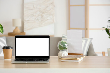 Blank laptop with coffee cup and plant on programmer's desk in living room