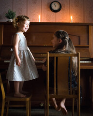 Children two girls playing an old piano and singing at home