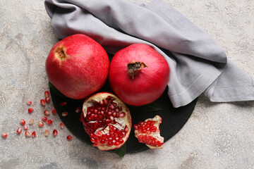 Black board with fresh ripe pomegranates and seeds on grey background