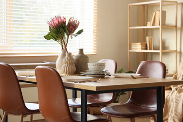 Table setting with vases and protea flowers in dining room