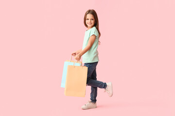 Obraz premium Happy little girl with shopping bags on pink background