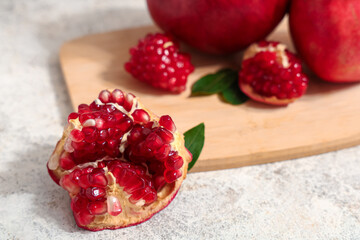 Wooden board with fresh ripe pomegranates on white background, closeup