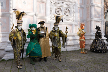 Obraz premium Venice, Italy - People dressed in carnival masks are photographed by tourists in the scenery of the ancient Venetian palaces