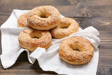 Tasty bagels with sesame seeds on wooden background, closeup