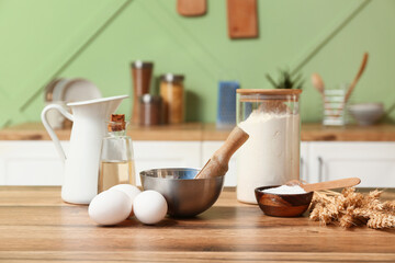 Fresh eggs, flour, baking soda and oil on wooden table in kitchen