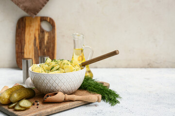 Bowl of tasty potato salad with dill, pickled cucumbers and peppercorns on light background