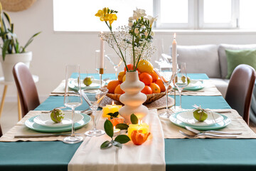 Beautiful table setting with citrus fruits and burning candles in living room