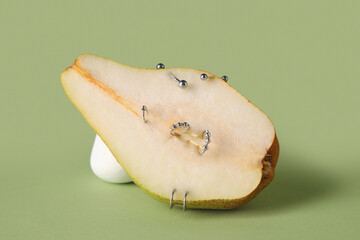 Half of pear with piercing on green background