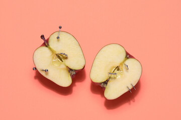 Halves of apple with piercing on orange background