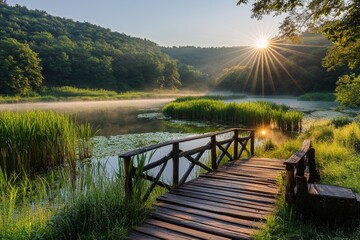 Sunrise over misty lake, wooden bridge through forest