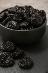 Black bowl with dried prunes on grey background, closeup