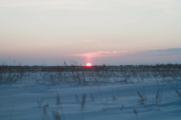 Frosty winter sunset in the field. Beautiful sunset in the snowy desert. Ice and sun..