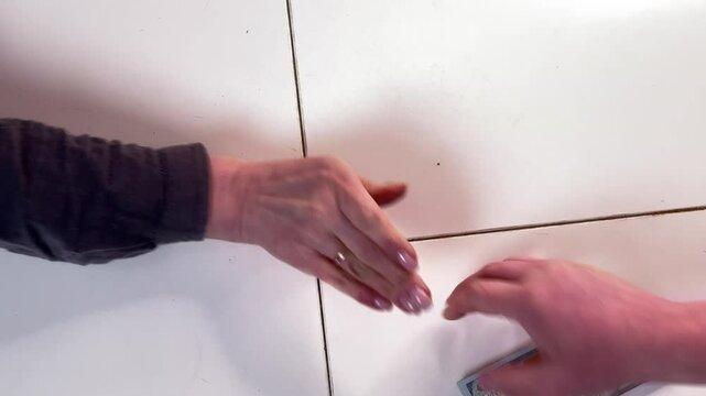 a man hands a woman a wad of dollars and they shake hand