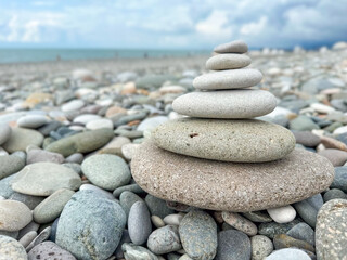 Stacked pebbles on pebbly beach with ocean background. Closeup of balanced pyramid stone stack on...