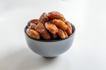 Delicious dates in a bowl on white