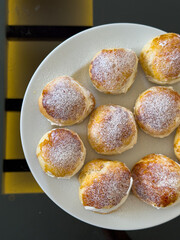 Homemade Berliner donuts pastries with powdered sugar and cream filling. Delicious Berliner or Krapfen buns dessert served on a white plate. Jam doughnut, German pastry and sweet concept