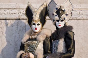 Venice, Italy - People dressed in carnival masks are photographed by tourists in the scenery of the ancient Venetian palaces