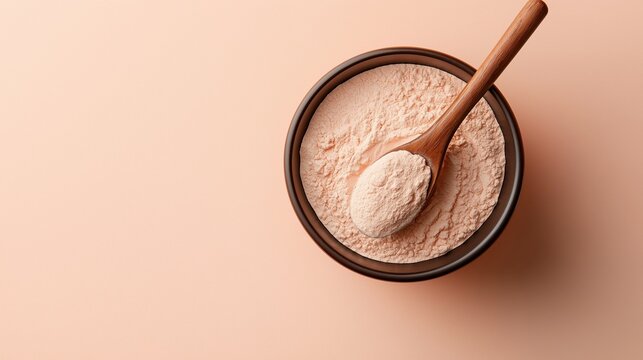 Small black bowl with a wooden spoon resting on top of it. the bowl is filled with a light pink powdery substance, which appears to be a type of flour.