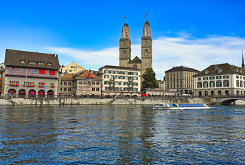 Historic Zurich city center with Grossmunster churh and a tourist boat sails on the river Limmat, Switzerland