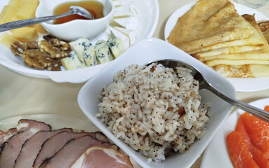 Delicious spread of dishes with rice, cured meat, assorted cheeses, and pancakes