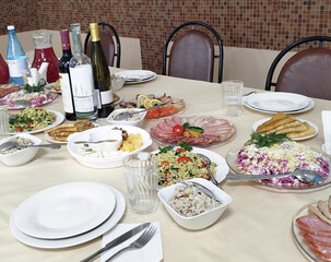 Dining table filled with diverse dishes and beverages at a gathering in a cozy setting