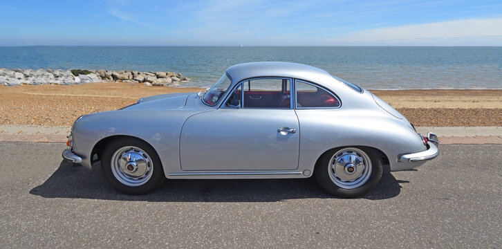 Classic Porsche 356 Coupe automobile parked on seafront  promenade with beach and sea in background.