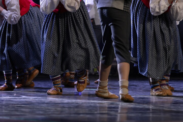 Close-up of dancers feet wearing traditional folk shoes and socks during a cultural dance performance on stage. The motion captures the rhythm and heritage of the dance. 