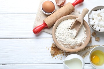 Rolling pin and ingredients for dough on white wooden table, flat lay. Space for text