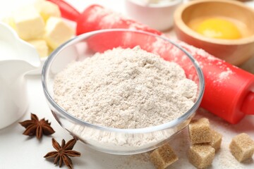 Rolling pin and different ingredients on white table, closeup