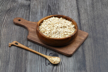 Oat flakes uncooked in a brown bowl on wooden table. Healthy food for breakfast