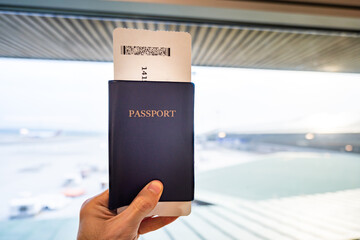Passport with boarding pass, or flight ticket, held in hand, at airport