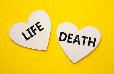 Life or Death symbol. Concept word Life or Death on wooden hearts. Beautiful yellow background....
