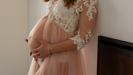Pregnant woman in lace dress holding her belly