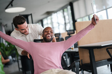 Obraz premium Two Male Colleagues Share a Joyful Moment in a Bright Office Space