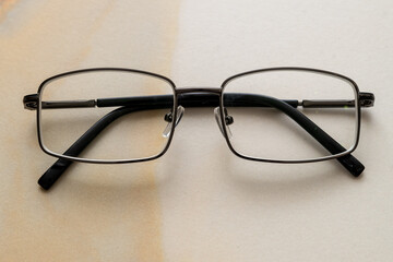 a pair of men's glasses with closed metal frames on a white marble table