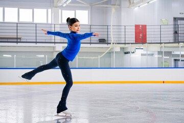 A young girl is skating on ice with a smile on her face.