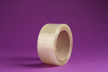 Roll of adhesive tape on violet background